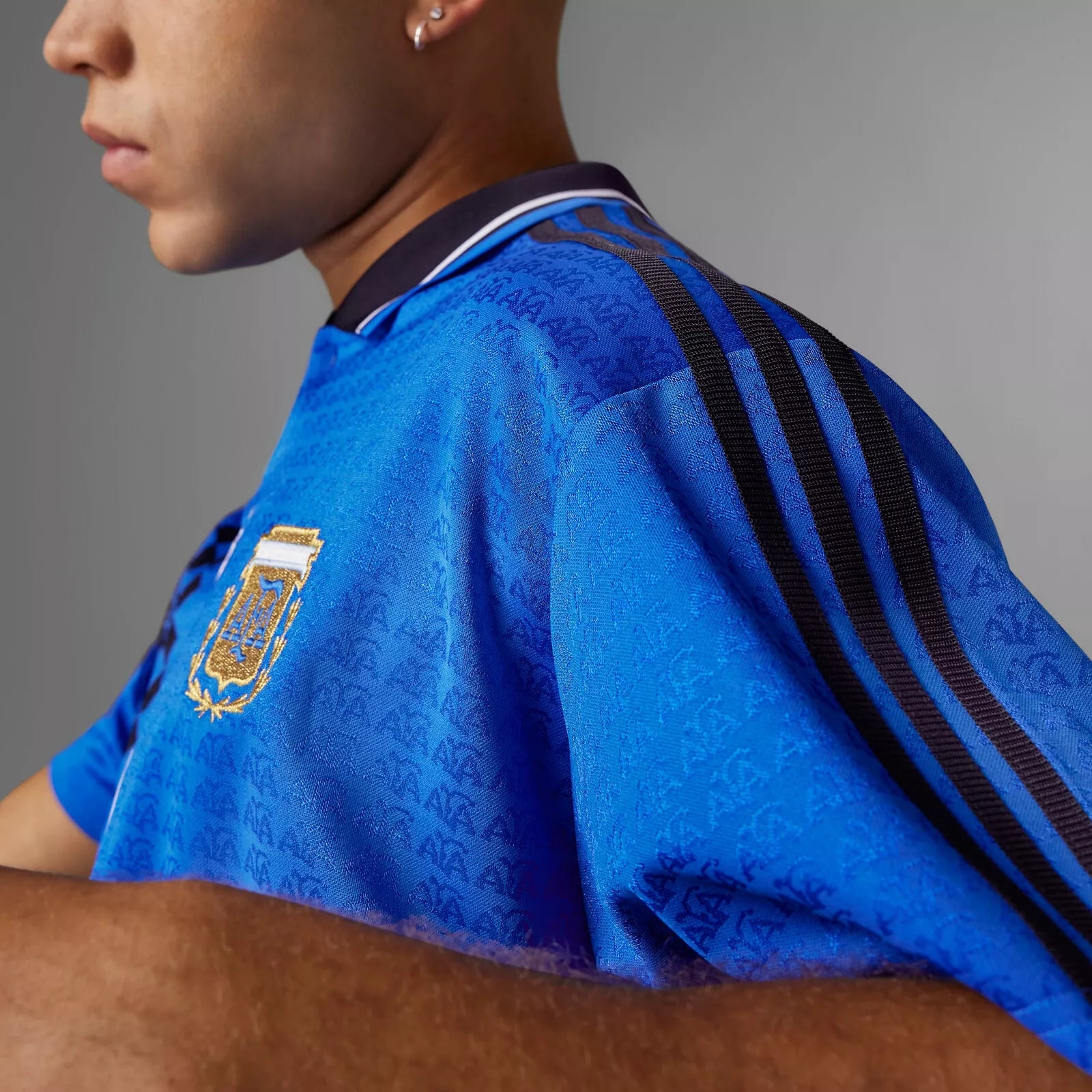 Person wearing a blue sports jersey with a logo on a gray background